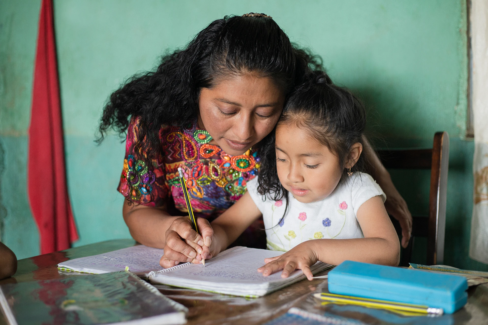 Madre enseñando a su hija a escribir